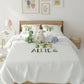 Children's bedroom with a bed featuring a white comforter with embroidered name 'ALFIE', surrounded by stuffed animals and decor.
