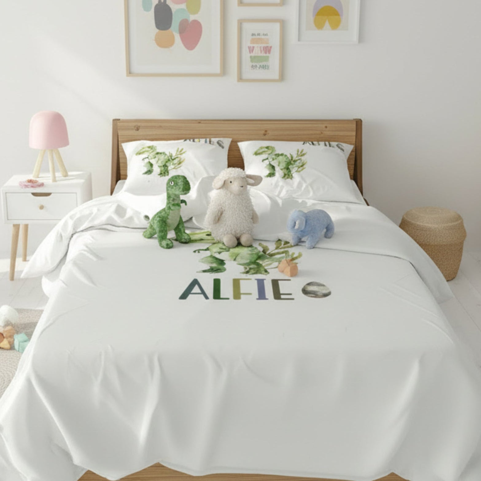 Children's bedroom with a bed featuring a white comforter with embroidered name 'ALFIE', surrounded by stuffed animals and decor.